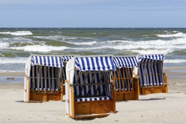 Orada plaj sandalye güneşin karşı koruyan küçük çatı Kolobrzeg, Polonya Baltık kıyısında kumlu bir plaj üzerinde yer alır.