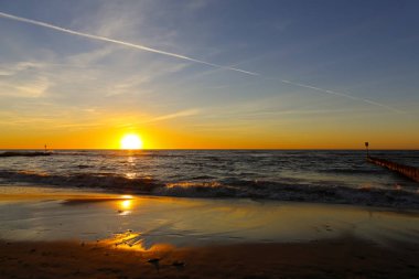 Batan güneşin Baltık Denizi karanlık suları yaklaşıyor ve bir kaç dakika içinde orada, Polonya Kolobrzeg sahil üzerinde görüldüğü gibi gizlemek