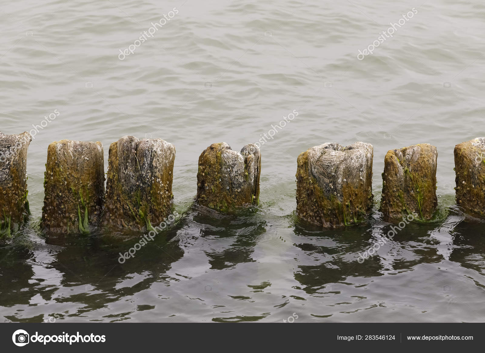 A Breakwater Is Visible Above The Calm Sea Waters Stock - 