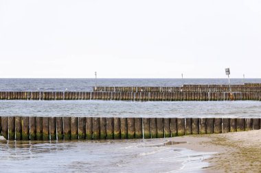 Deniz kıyısında kalın ahşap direkleri Satırlar