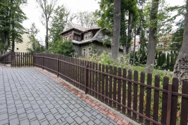 Çitin arkasından görülen eski bina