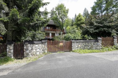 Ev sağlam bir taş çitin arkasında.