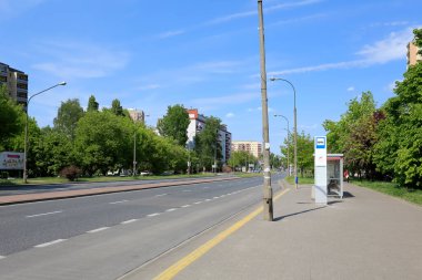 Varşova, Polonya - 10 Mayıs 2020: Geniş caddenin karşısında gür bitki örtüsüyle çevrili yerleşim binaları var. Devam eden salgın sırasında gözle görülür bir trafik eksikliği var.
