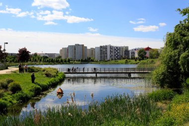 Varşova, Polonya - 22 Mayıs 2020: Göl üzerindeki dar bir yaya köprüsü Goclaw konutlarında görülebilen park alanlarında görülüyor.
