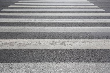 Siyah asfalt üzerinde beyaz çizgili bir yaya geçidi..