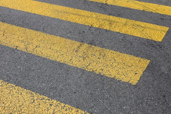 Siyah asfalttaki sarı çizgiler yaya geçidi..