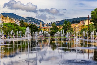 Nice, France - May 24, 2018: Reflecting fountain on Promenade du Paillon, surrounded by beautiful historic buildings and green urban park at Place Massena or Massena square clipart
