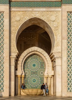 Casablanca, Fas - 09 Aralık 2012: Arabesque mozaik tasarımı Fountain'dan ot cami Hassan II ve üzerine oturan insanlar