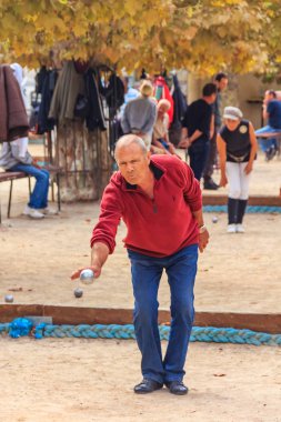 Cannes, France - October 17, 2013: Senior man plays petanque with a metal ball in a park clipart