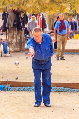 Cannes, France - October 17, 2013: Senior man plays petanque with a metal ball in a park clipart