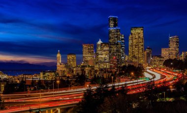 Seattle şehir manzarası ve gökdelenler ötesinde mavi saatte uzun pozlama trafik iz ışıkları Dr Jose Rizal veya 12 Avenue South Bridge ile güneş battıktan sonra I-5 I-90 çevre yolu Kavşağı