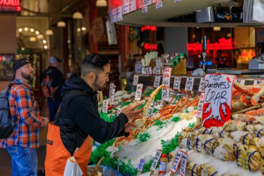 Seattle, Amerika Birleşik Devletleri - 08 Kasım 2018: Taze yengeç bacakları buz bir ahır Satılık Pike Place Market arka planda bir müşteriyle koyarak balık satıcısı