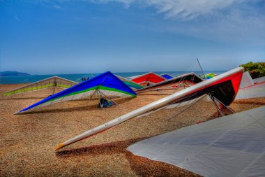 Colorful hang gliding wings lined up on top of a cliff at Fort Funston in San Francisco, one of the premier hang-gliding spots in the country clipart