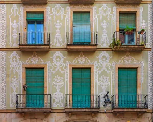 Ornate painted residential building facade and windows with green wooden shutters in the Gothic Quarter in Barcelona, Spain
