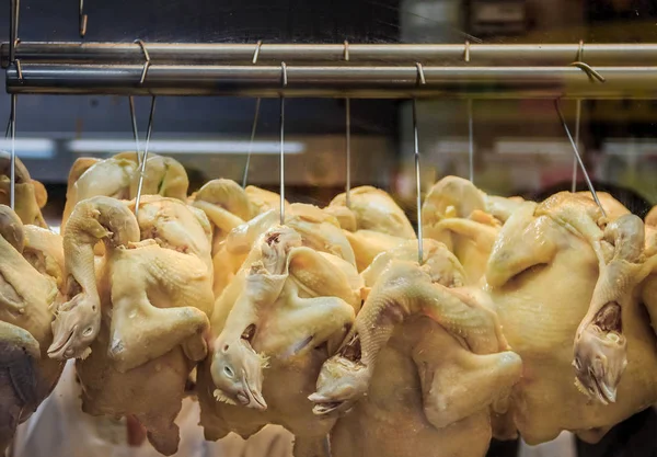 Whole poached chickens with heads hanging at a Hainanese Chicken Rice hawker stall in Singapore — Stock Photo, Image