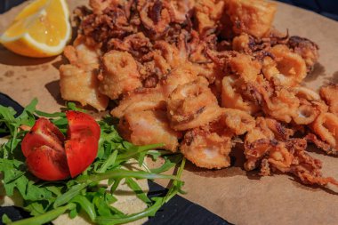 Çıtır çıtır kızarmış kalamar bir tahta üzerine limon ve roka ve domates Ventimiglia, İtalya bir restoranda bir salata ile servis