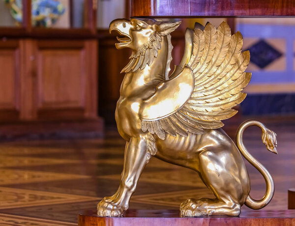 Ornate table leg in the shape of a golden gryphon in Winter Pala