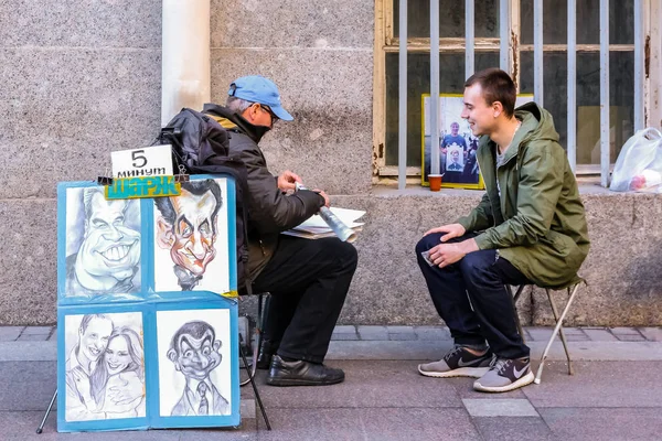 Retratista de caricatura callejera con un turista dibujando su retrato cerca de la Plaza del Palacio en San Petersburgo, Rusia — Foto de Stock