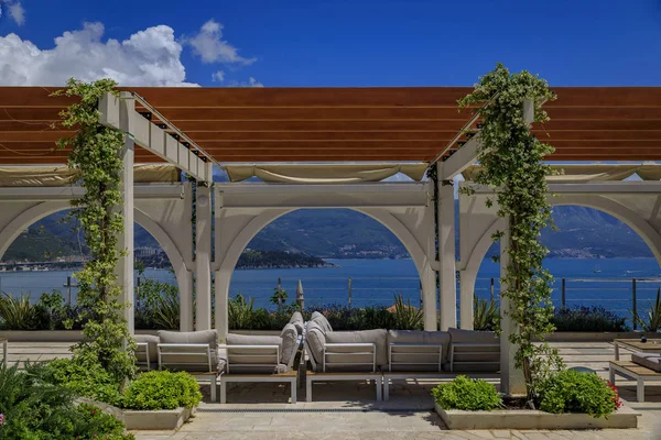 Outdoor seating in a restaurant in Budva with a view of Old Town and the Adriatic Sea in Montenegro on a sunny day