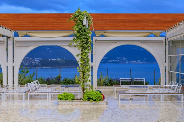 Outdoor seating in a restaurant in Budva with the view of the Old Town and the Adriatic Sea in Montenegro at sunset
