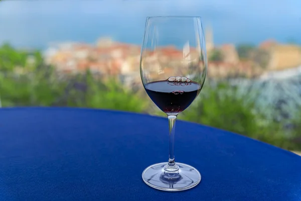 Sklenice místního červeného vína na stole v restauraci s Budva starým městem a Jaderským mořem v Černé hoře v pozadí — Stock fotografie
