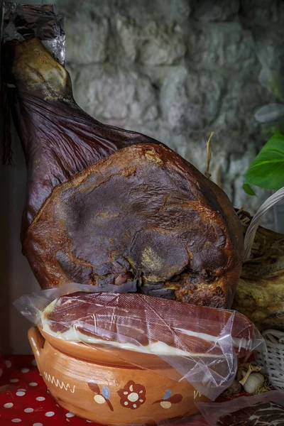 Whole bone-in ham leg of Montenegrin Njeguski prsut cured ham and sliced packaged meat at a market in Kotor Montenegro — Stock Photo, Image