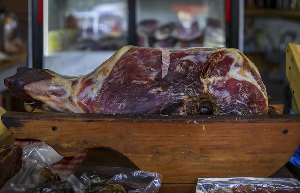 Hele been-in ham poot van Montenegrijnse Njeguski prsut gezouten ham en gesneden verpakt vlees op een markt in Kotor Montenegro — Stockfoto