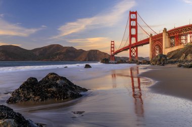 San Francisco, Kaliforniya'da gün batımında gizli ve tenha kayalık Marshall Plajı Golden Gate Köprüsü görünümü