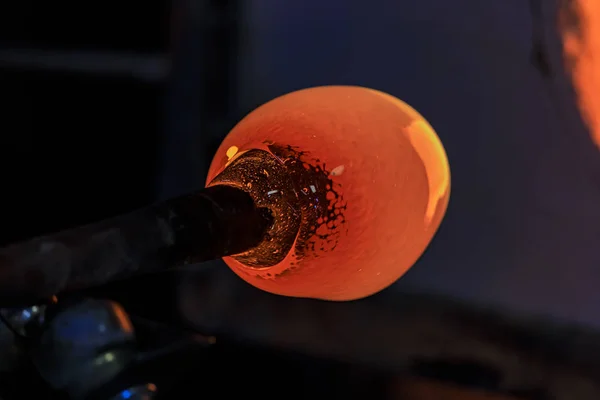 Soprador de vidro trabalhando em uma bolha de vidro derretido em uma haste, aquecendo-o em um forno na oficina de um fabricante de vidro — Fotografia de Stock