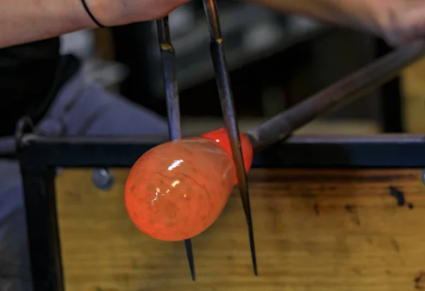 Glass blower shaping a bubble of melted glass on a rod by hand at a glass maker's workshop, shallow depth of field — Stock Photo, Image