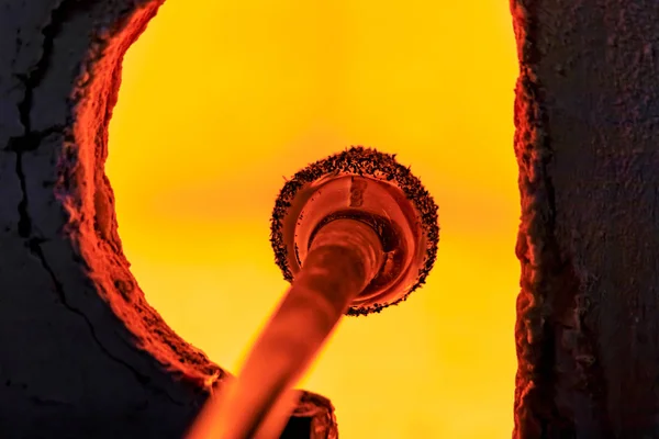 Soprador de vidro trabalhando em uma bolha de vidro derretido em uma haste, aquecendo-o em um forno na oficina de um fabricante de vidro — Fotografia de Stock