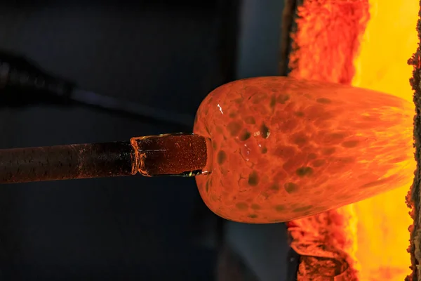 Soplador de vidrio que trabaja en una burbuja de vidrio fundido en una varilla calentándolo en un horno en el taller de un fabricante de vidrio —  Fotos de Stock