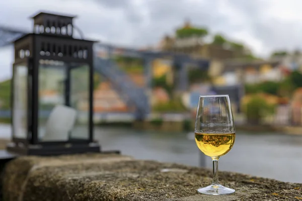 Glass of port wine with the blurred cityscape of Porto Portugal and a lantern in the background