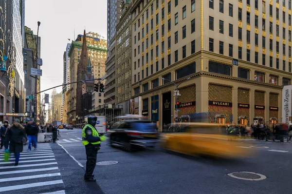 Размытые желтые такси проезжают мимо людей и дорожного патруля на пересечении 5-й авеню в Манхэттене, Нью-Йорк, США — стоковое фото