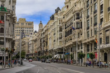 Ünlü Gran Via alışveriş caddesindeki güzel binalar ve Madrid 'in merkezinde yürüyen insanlar.