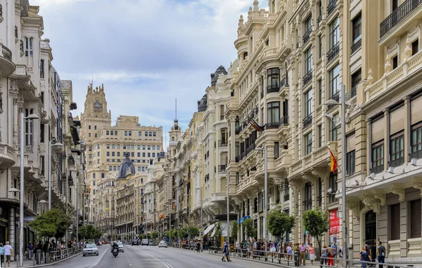 Hermosos edificios en la famosa calle comercial Gran Vía y gente caminando por el centro de la ciudad en Madrid, España — Foto de Stock