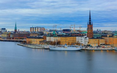 Stockholm, İsveç - 24 Ekim 2017: Malaren Gölü 'nün karşısındaki panoramik manzara eski kasaba Gamla Stan ve Riddarholmen kilisesindeki geleneksel gotik binalar,