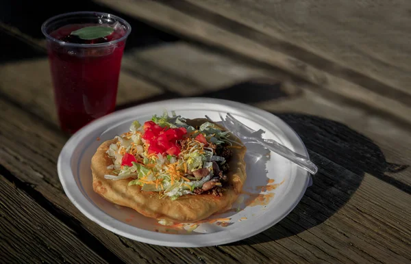 stock image Traditional Indian Taco made of fry bread and beef and a Native American blackberry sage ice tea with fresh berries and sage at powwow, San Francisco