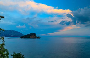 Budva Karadağ yakınlarındaki Adriyatik Denizi 'nde küçük bir ada olan St. Nicholas veya Hawaii adasının renkli günbatımı manzarası