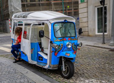 Portekiz 'in Porto kentinde turistleri bekleyen eski şehir merkezinde tipik bir kaldırımlı caddede renkli tuktuk.