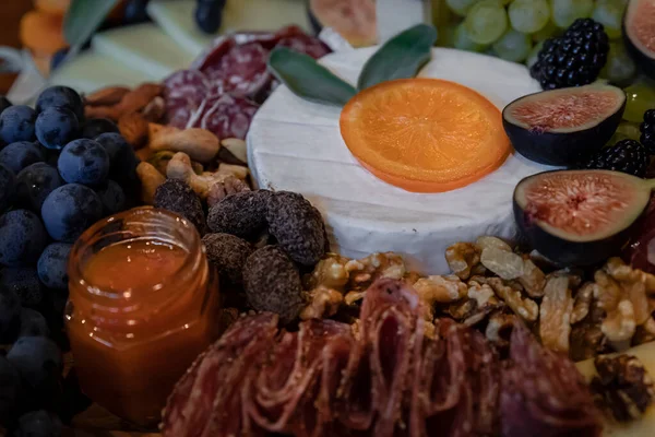 Food board with cured meats prosciutto, salami and coppa, brie, cheddar and other cheeses and fruits decorated with sage — Stock Photo, Image