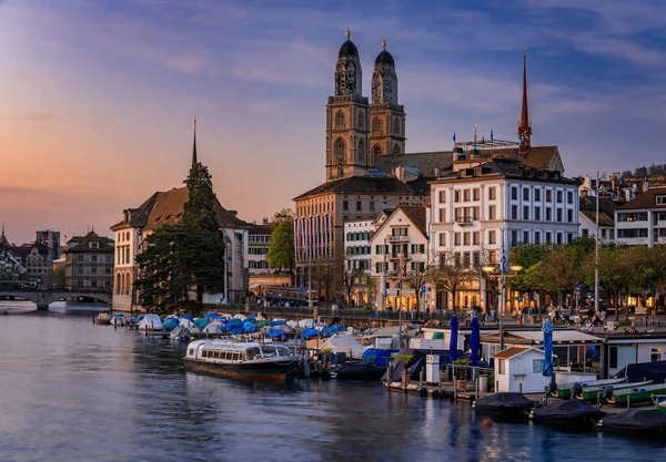 İsviçre, Zürih şehri, alacakaranlıkta. Limmat Nehri 'nin kıyısındaki binalar Altstadt şehir merkezinden akıyor, tekneler liman boyunca akıyor.