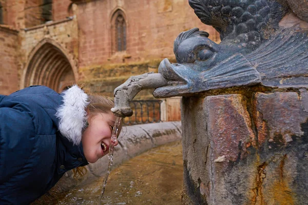 スペインの古い中世の泉を飲む金髪子供女の子 — ストック写真