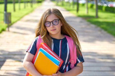 Sarışın çocuk öğrenci kızla gözlük defter ve parkta sırt çantası