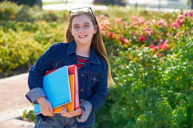Sarışın çocuk öğrenci kızla defter ve okul için parkta sırt çantası