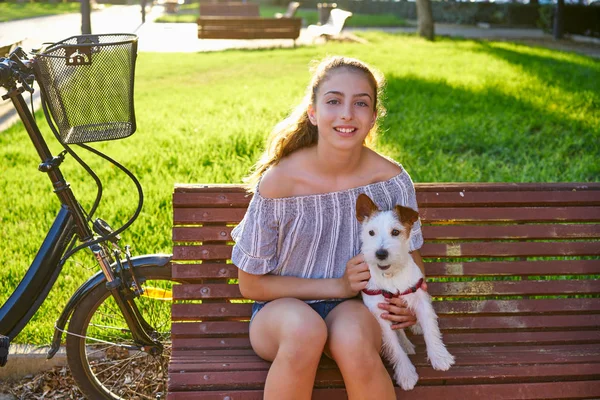 屋外芝生草の背景と公園のベンチに座っている犬を持つ少女 — ストック写真
