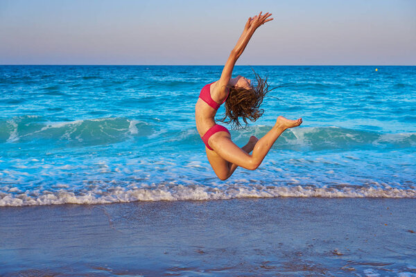 acrobatic gymnastics bikini girl in a beach blue shore at summer