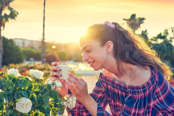 Mädchenporträt Beim Fotografieren Einer Rosenblume Mit Dem Smartphone — Stockfoto