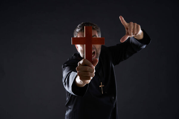 Priest holding cross of wood praying in foreground