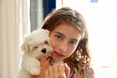 Maltichon beyaz bir köpek yavrusu gülümseyen kız çocuk